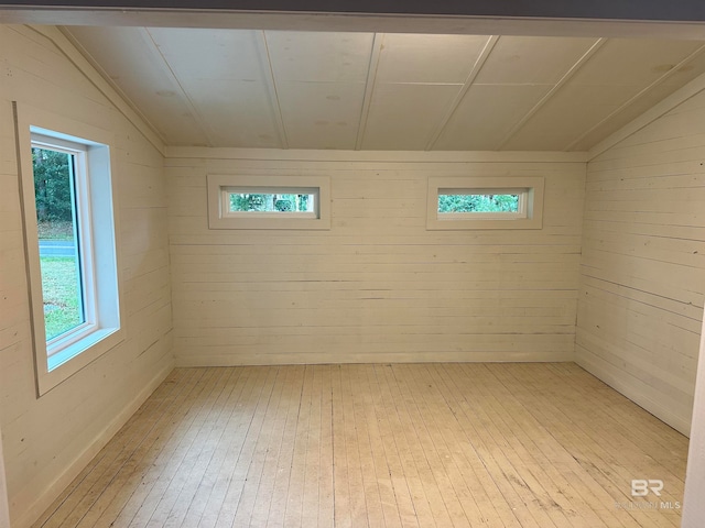 basement with light wood-type flooring and wooden walls