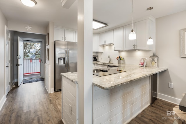 kitchen with wood finished floors, a peninsula, stainless steel fridge, white cabinets, and tasteful backsplash