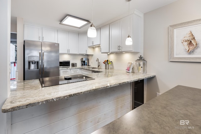 kitchen with decorative backsplash, a peninsula, white cabinets, and appliances with stainless steel finishes