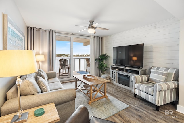 living area featuring wood finished floors, wood walls, and ceiling fan