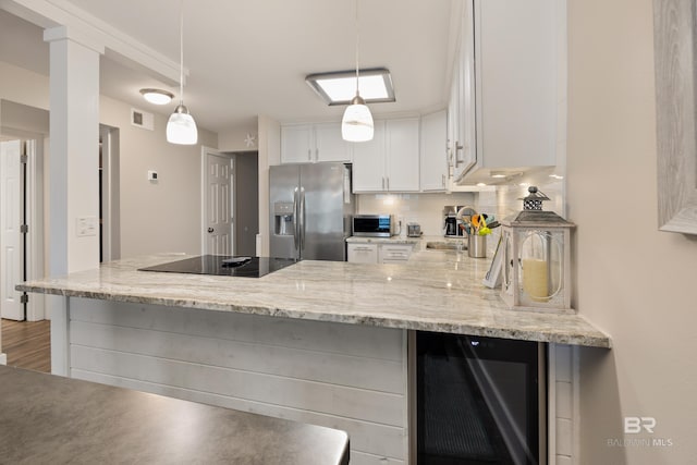 kitchen with visible vents, a sink, backsplash, stainless steel fridge, and black electric stovetop