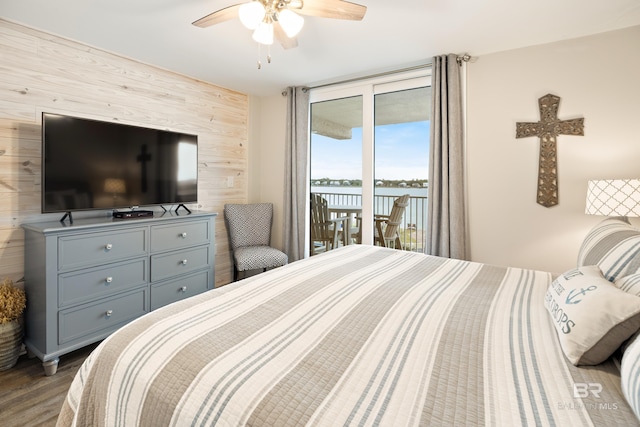 bedroom with a ceiling fan, wood finished floors, wooden walls, access to exterior, and an accent wall