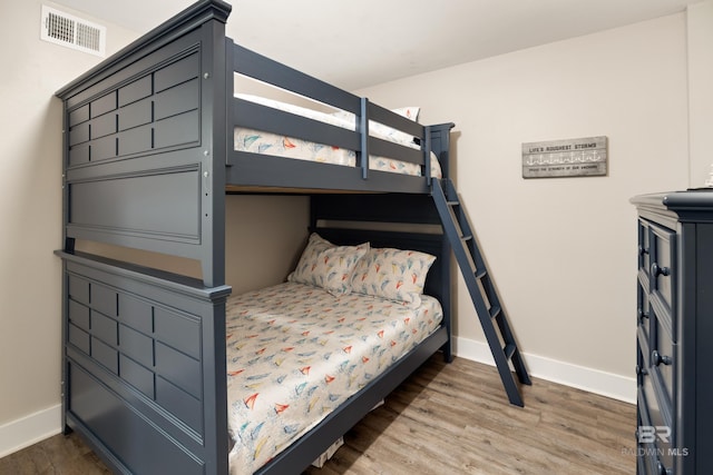 bedroom with visible vents, baseboards, and wood finished floors