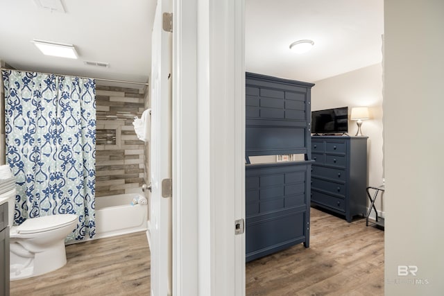 bathroom featuring visible vents, toilet, wood finished floors, shower / tub combo, and vanity