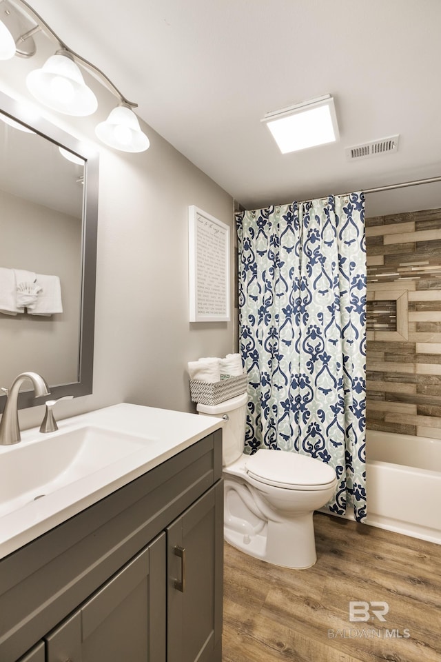 bathroom with visible vents, toilet, shower / bath combo, wood finished floors, and vanity