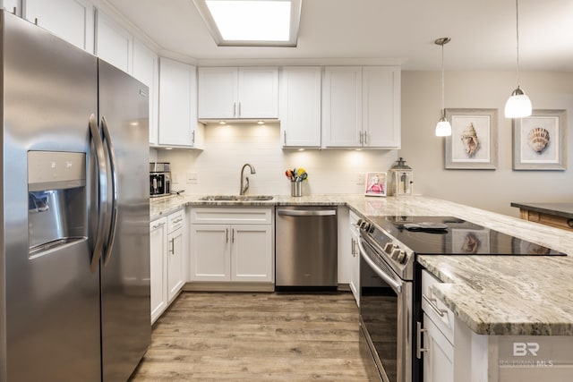 kitchen featuring white cabinetry, a peninsula, appliances with stainless steel finishes, and a sink