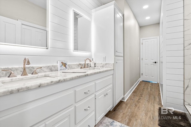 full bathroom with baseboards, double vanity, recessed lighting, a sink, and wood finished floors