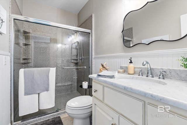 full bathroom featuring toilet, a shower stall, wainscoting, and vanity