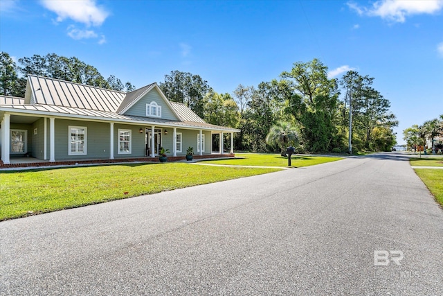 view of front of house with metal roof, a front lawn, covered porch, and a standing seam roof
