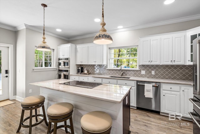 kitchen with white cabinets, light wood finished floors, a sink, and appliances with stainless steel finishes