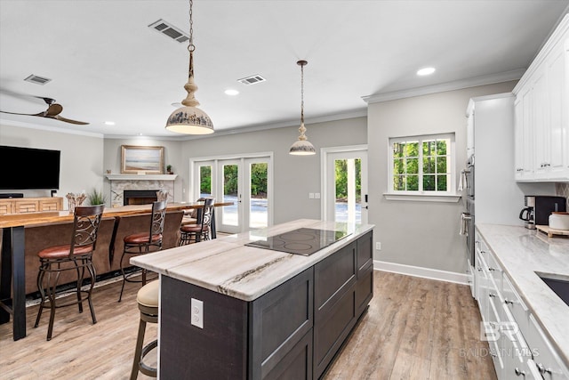 kitchen with ornamental molding, visible vents, white cabinets, and a breakfast bar