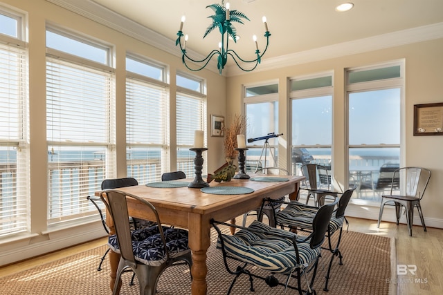 dining area with an inviting chandelier, crown molding, light wood-type flooring, and plenty of natural light