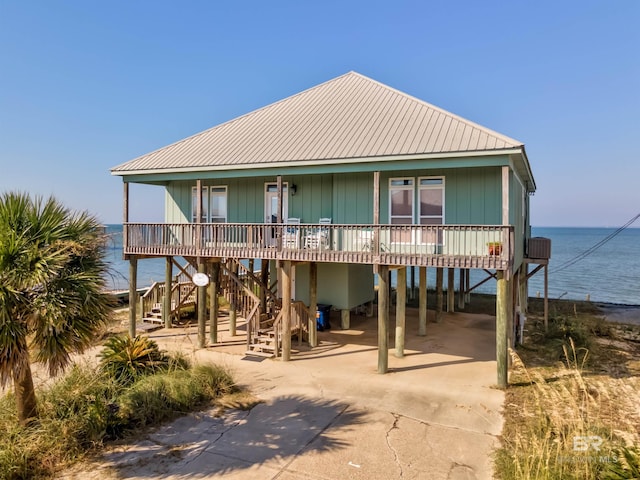 coastal home with covered porch, a water view, and a carport