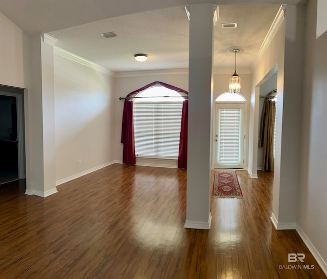 foyer featuring ornate columns, crown molding, and dark wood-type flooring