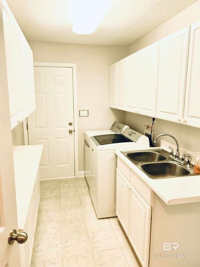 laundry room featuring cabinets, sink, a textured ceiling, and washer and clothes dryer