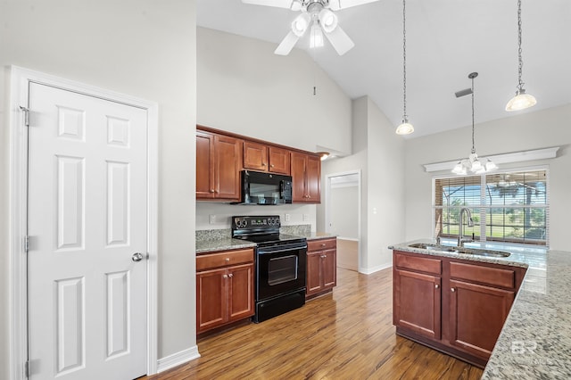 kitchen featuring black appliances, hardwood / wood-style floors, sink, pendant lighting, and light stone counters