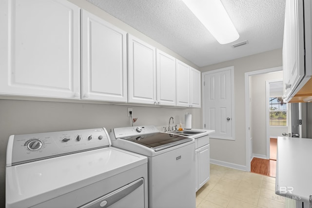 laundry area featuring cabinets, sink, a textured ceiling, and washer and clothes dryer