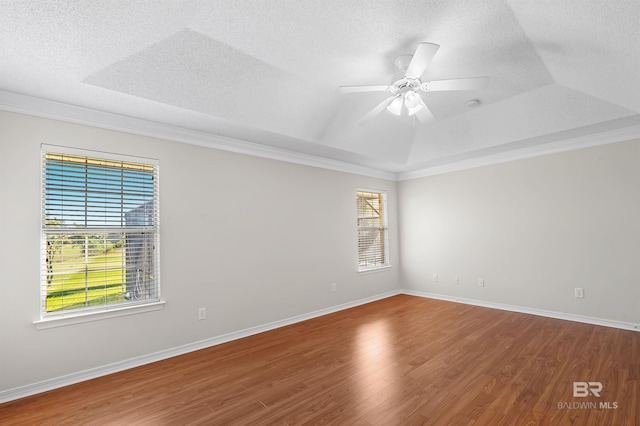 unfurnished room featuring hardwood / wood-style flooring, ornamental molding, a raised ceiling, and ceiling fan