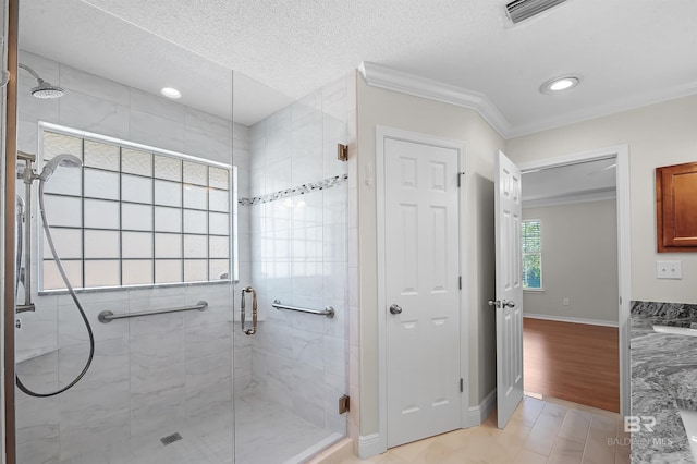 bathroom with vanity, a shower with shower door, ornamental molding, and a textured ceiling