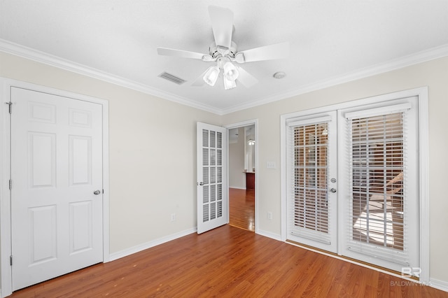 empty room featuring ornamental molding, hardwood / wood-style floors, ceiling fan, and french doors