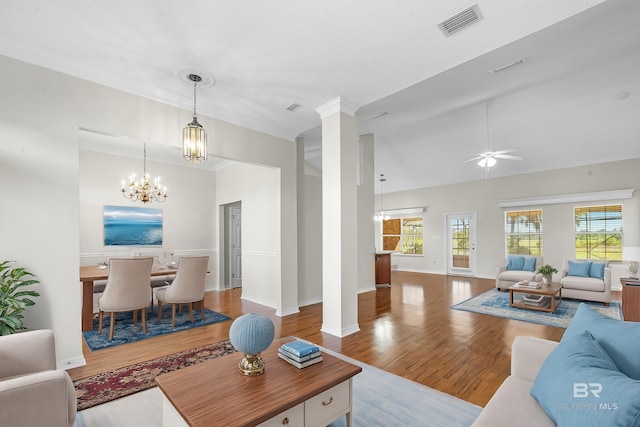 living room featuring vaulted ceiling, ceiling fan with notable chandelier, ornate columns, and wood-type flooring