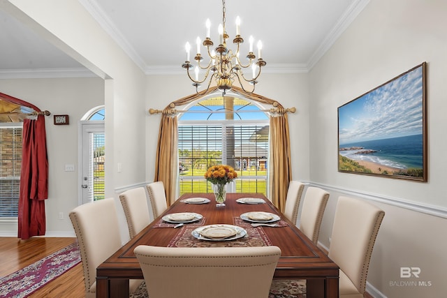 dining space featuring wood-type flooring, an inviting chandelier, and ornamental molding