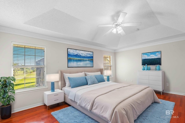 bedroom with ceiling fan, a tray ceiling, dark hardwood / wood-style floors, and crown molding