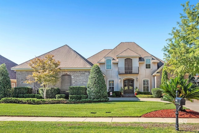 french country style house with a balcony and a front lawn