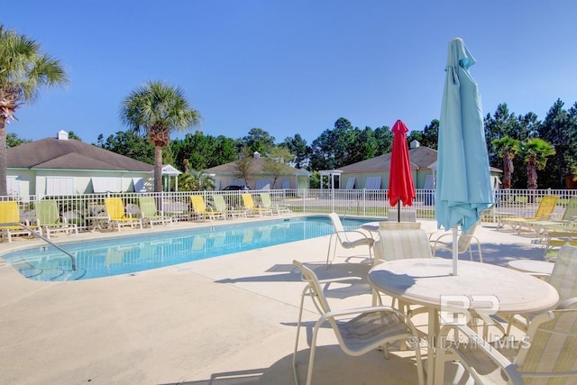 community pool with a patio area and fence