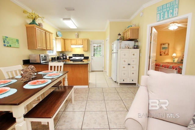 kitchen with light tile patterned floors, range with electric cooktop, stainless steel microwave, and light brown cabinets