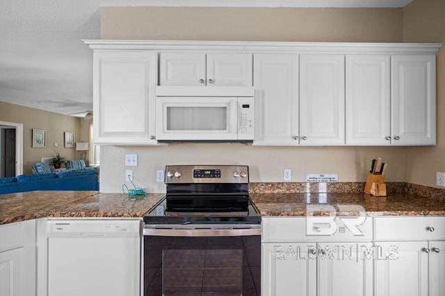 kitchen with dark stone countertops, white appliances, and white cabinetry