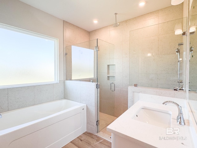 bathroom with a bath, a stall shower, recessed lighting, wood finished floors, and vanity