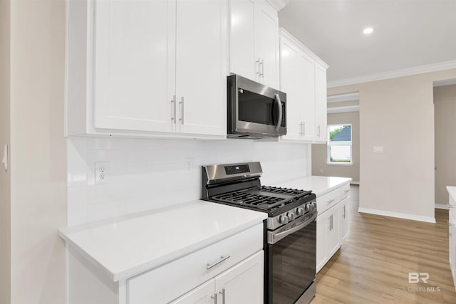 kitchen with backsplash, light countertops, crown molding, baseboards, and appliances with stainless steel finishes