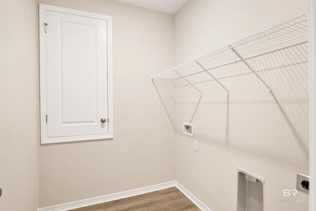 laundry room featuring laundry area, wood finished floors, hookup for an electric dryer, hookup for a washing machine, and baseboards