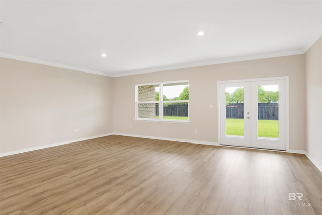 empty room with baseboards, a healthy amount of sunlight, crown molding, and light wood-type flooring