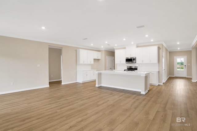 kitchen featuring light wood-type flooring, appliances with stainless steel finishes, baseboards, and ornamental molding