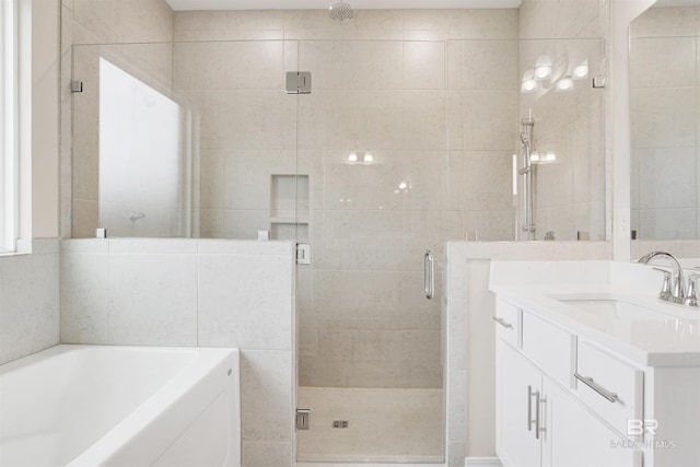 full bath featuring a garden tub, vanity, and a stall shower