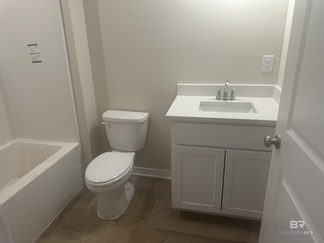 bathroom featuring vanity, a tub to relax in, and toilet