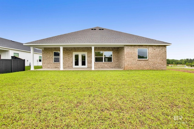 rear view of house featuring a patio area, brick siding, a yard, and roof with shingles