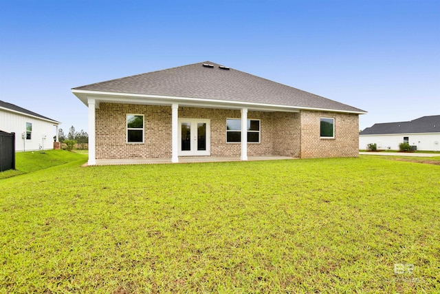 rear view of property with brick siding, a yard, french doors, and a patio area