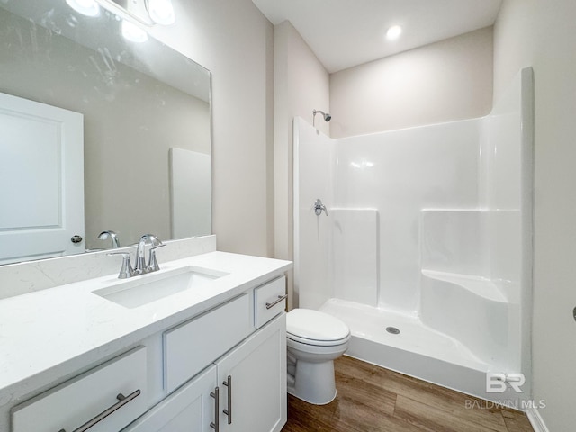 full bathroom featuring wood finished floors, vanity, toilet, and walk in shower