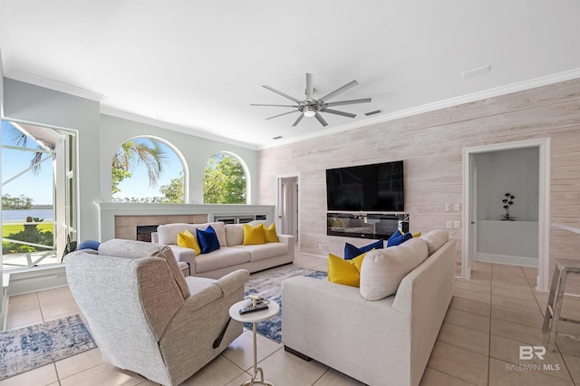 8160 Bay View Dr, Foley, AL 36535 - living room featuring a fireplace, crown molding, light tile patterned floors, a ceiling fan, and wooden walls