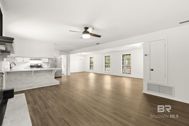 unfurnished living room featuring dark hardwood / wood-style flooring and ceiling fan with notable chandelier