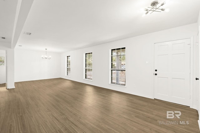 unfurnished living room with dark wood-type flooring and a notable chandelier