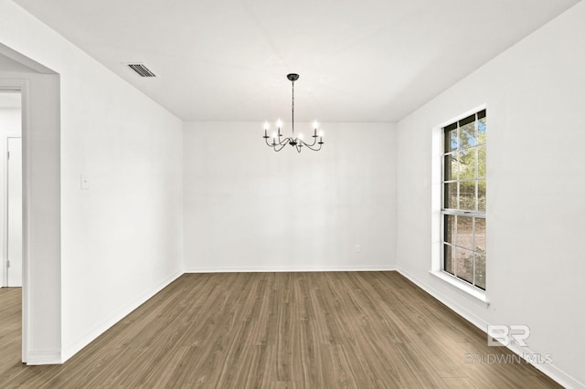 empty room featuring plenty of natural light, a chandelier, and hardwood / wood-style floors