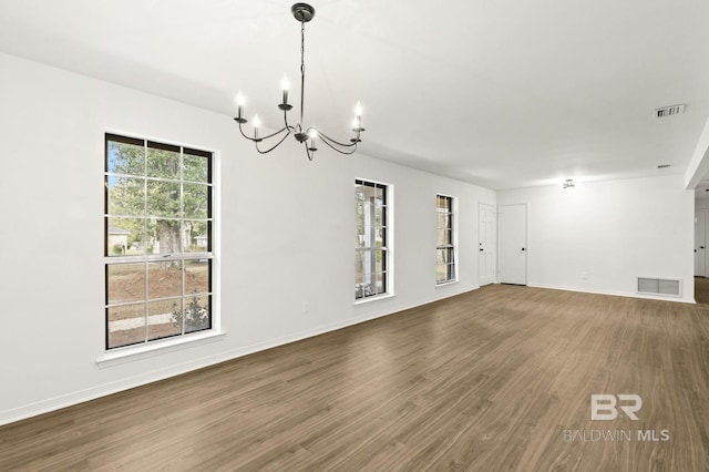 spare room featuring a notable chandelier and dark hardwood / wood-style floors