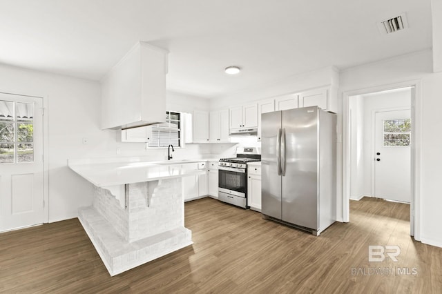 kitchen with a breakfast bar, stainless steel appliances, white cabinetry, and kitchen peninsula