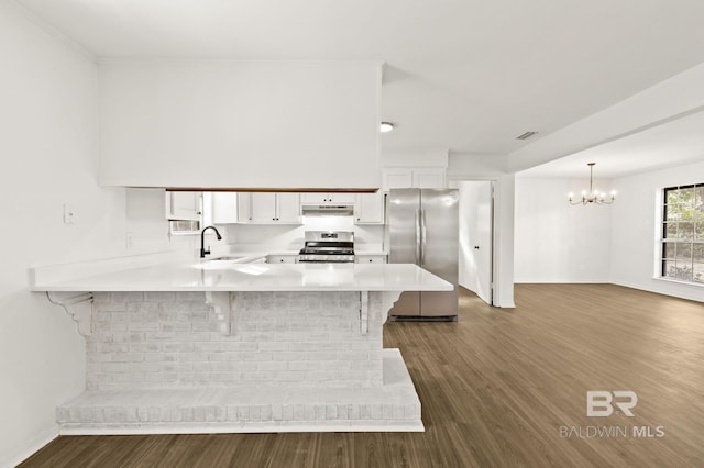 kitchen with a breakfast bar area, stainless steel appliances, kitchen peninsula, pendant lighting, and white cabinetry