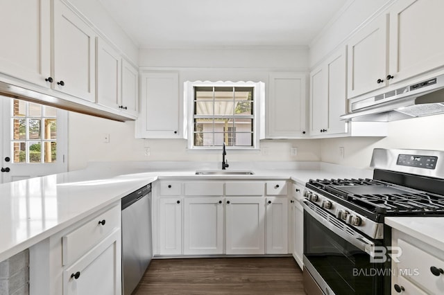 kitchen with stainless steel appliances, sink, white cabinets, kitchen peninsula, and dark hardwood / wood-style flooring