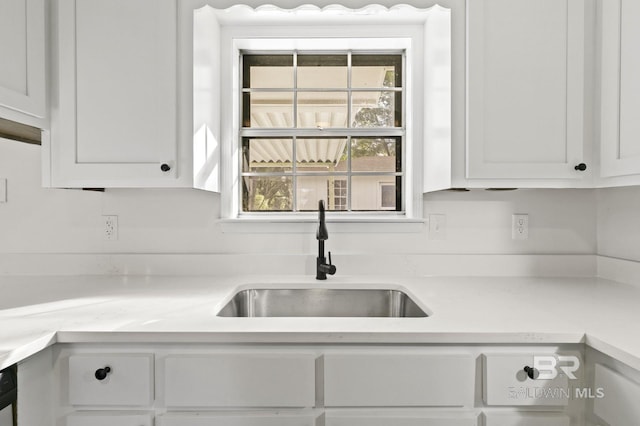 kitchen with sink, white cabinets, and light stone counters